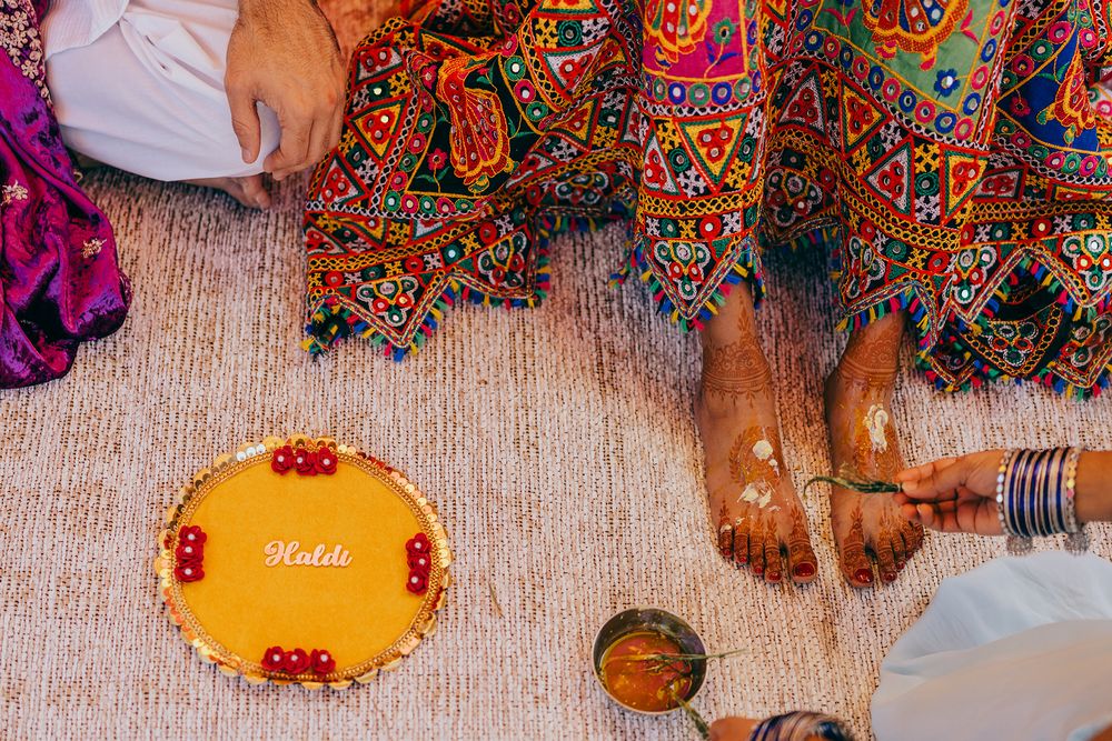 Colorful Indian wedding ceremony with traditional decorations and rituals being performed on a wooden floor.
