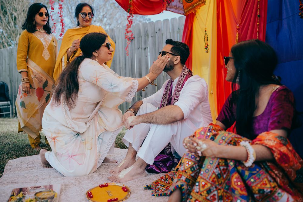 Celebratory gathering at an outdoor Indian wedding ceremony with colorful decorations and traditional attire.