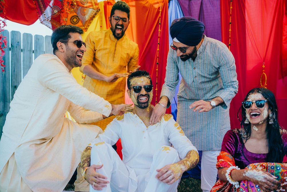 Vibrant Indian wedding celebration with guests in traditional attire dancing and celebrating against colorful backdrop.
