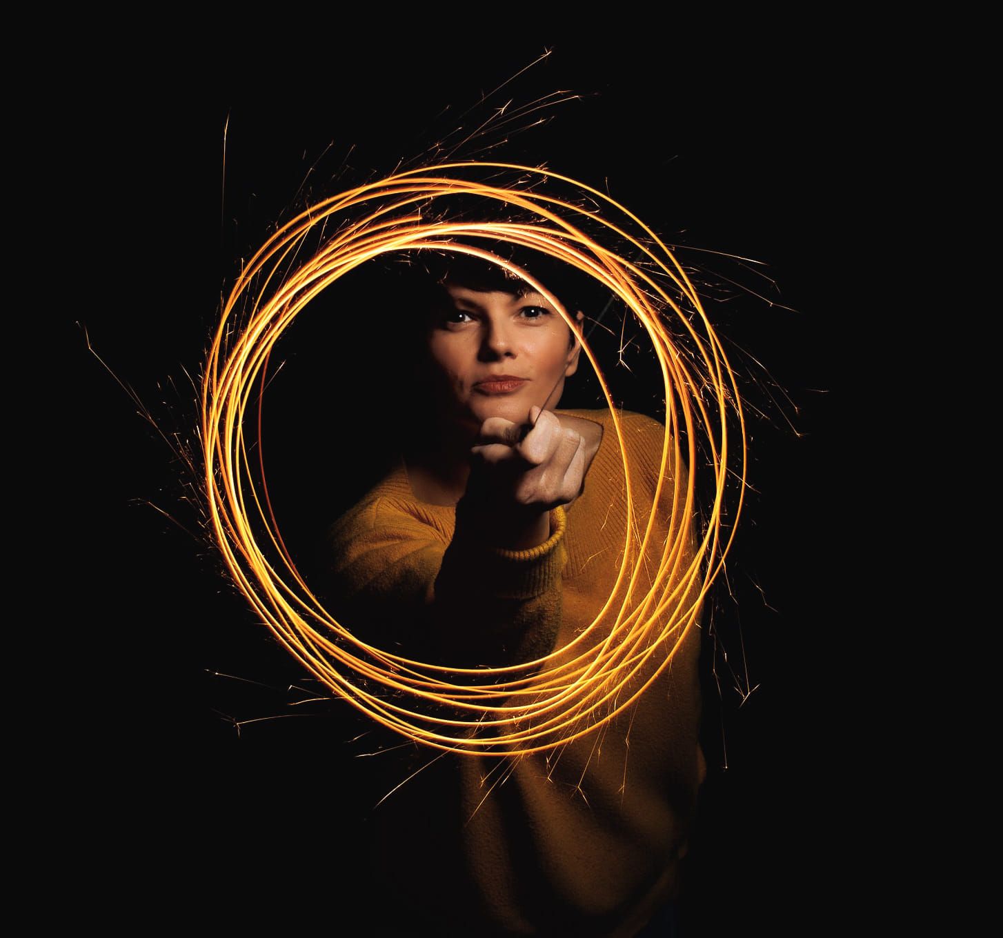 Portrait of photographer holding professional camera lens in dark setting with dramatic lighting.