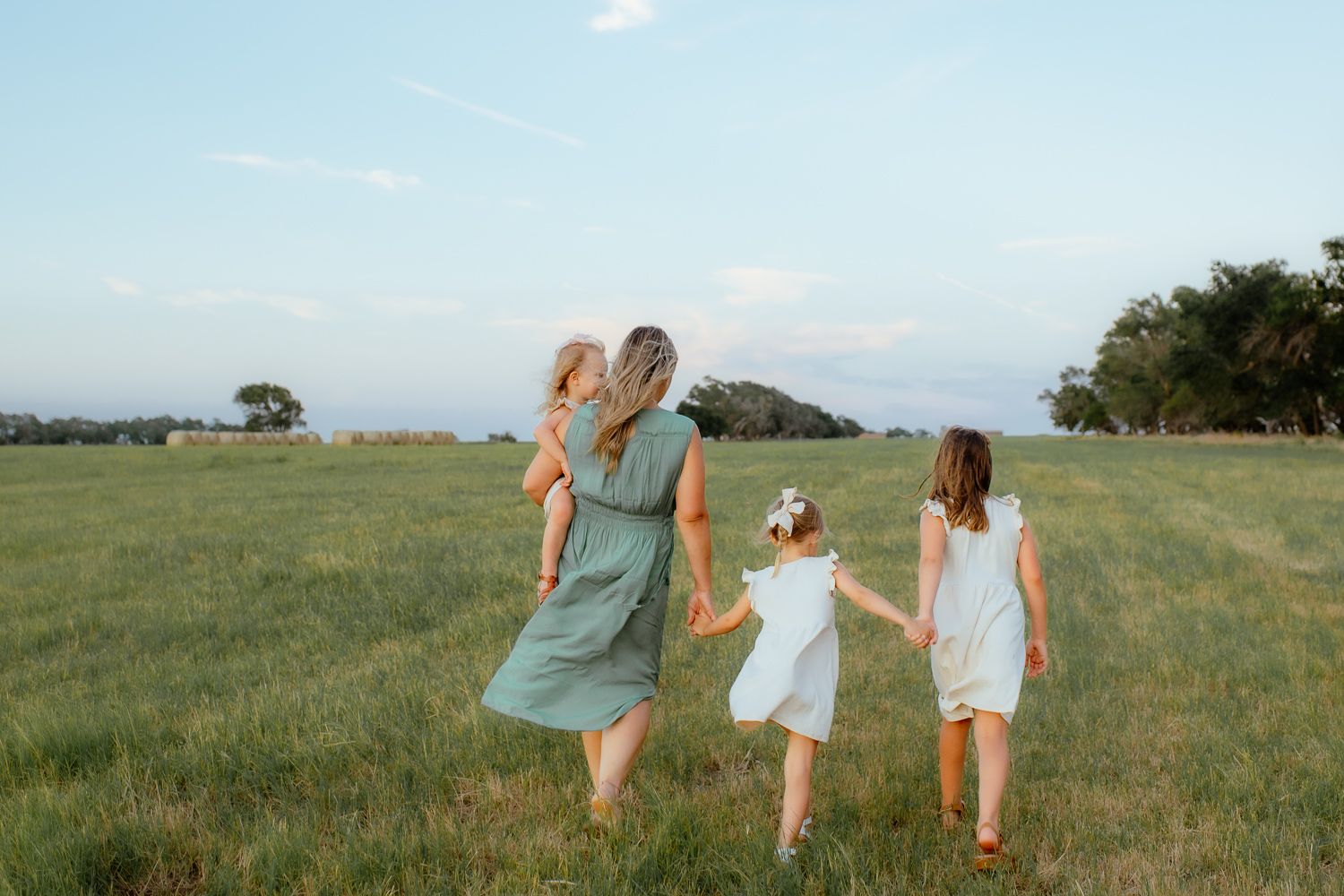 Mom and 3 girls walking and holding hands during their mommy and me photoshoot with an Enid family photographer.