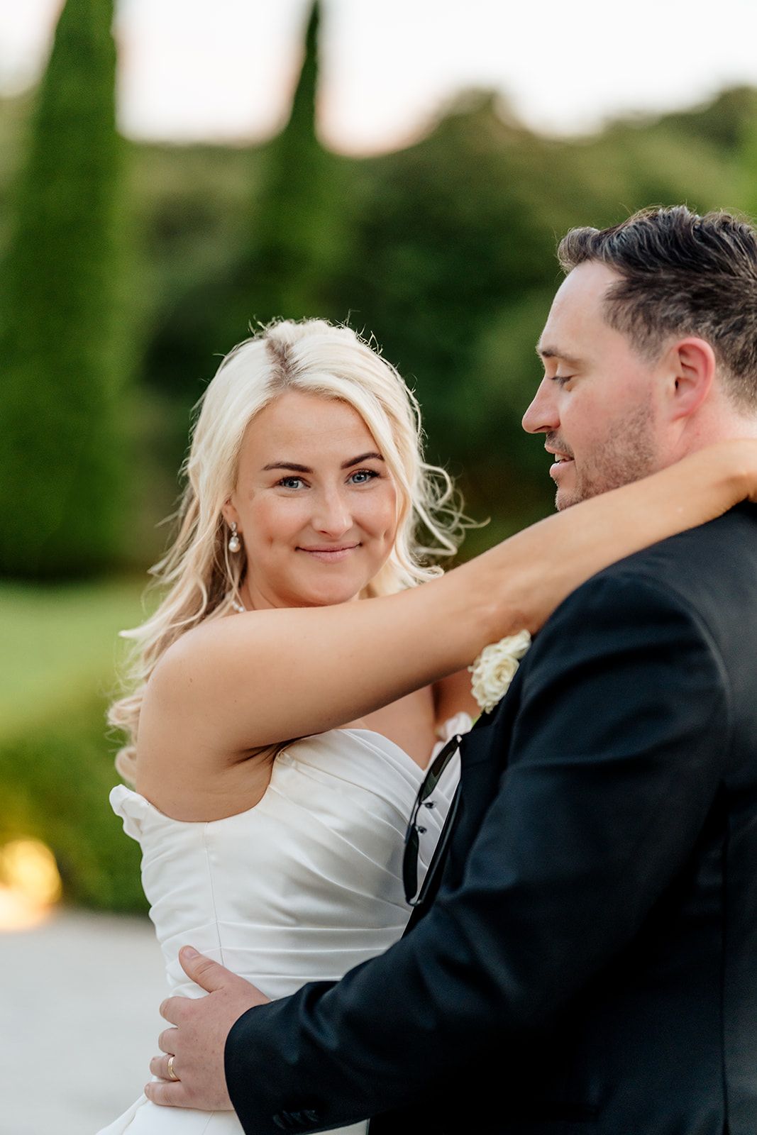 A romantic moment captured between a couple on their wedding day with greenery in the background.