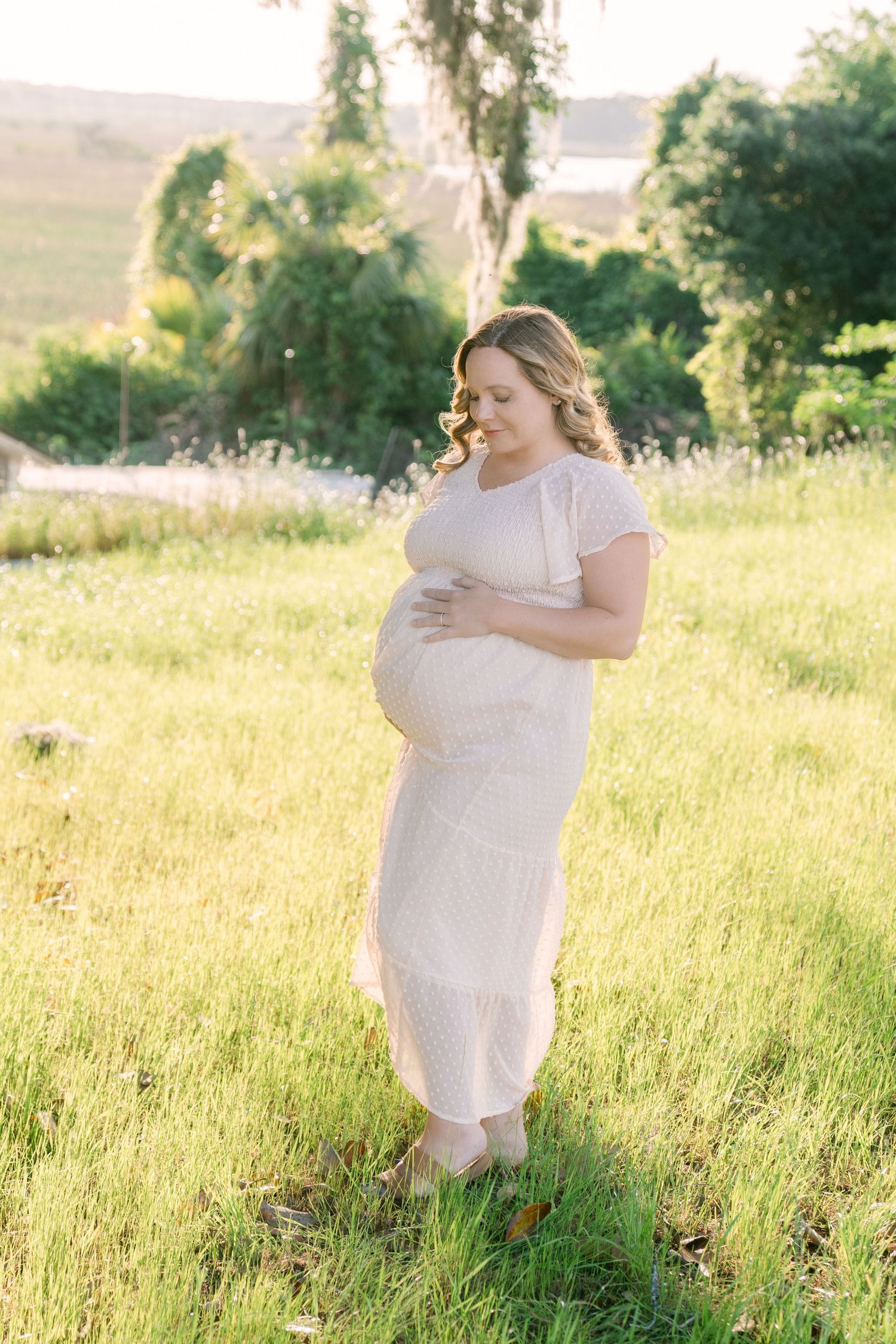 Expecting mother in flowing dress by the water