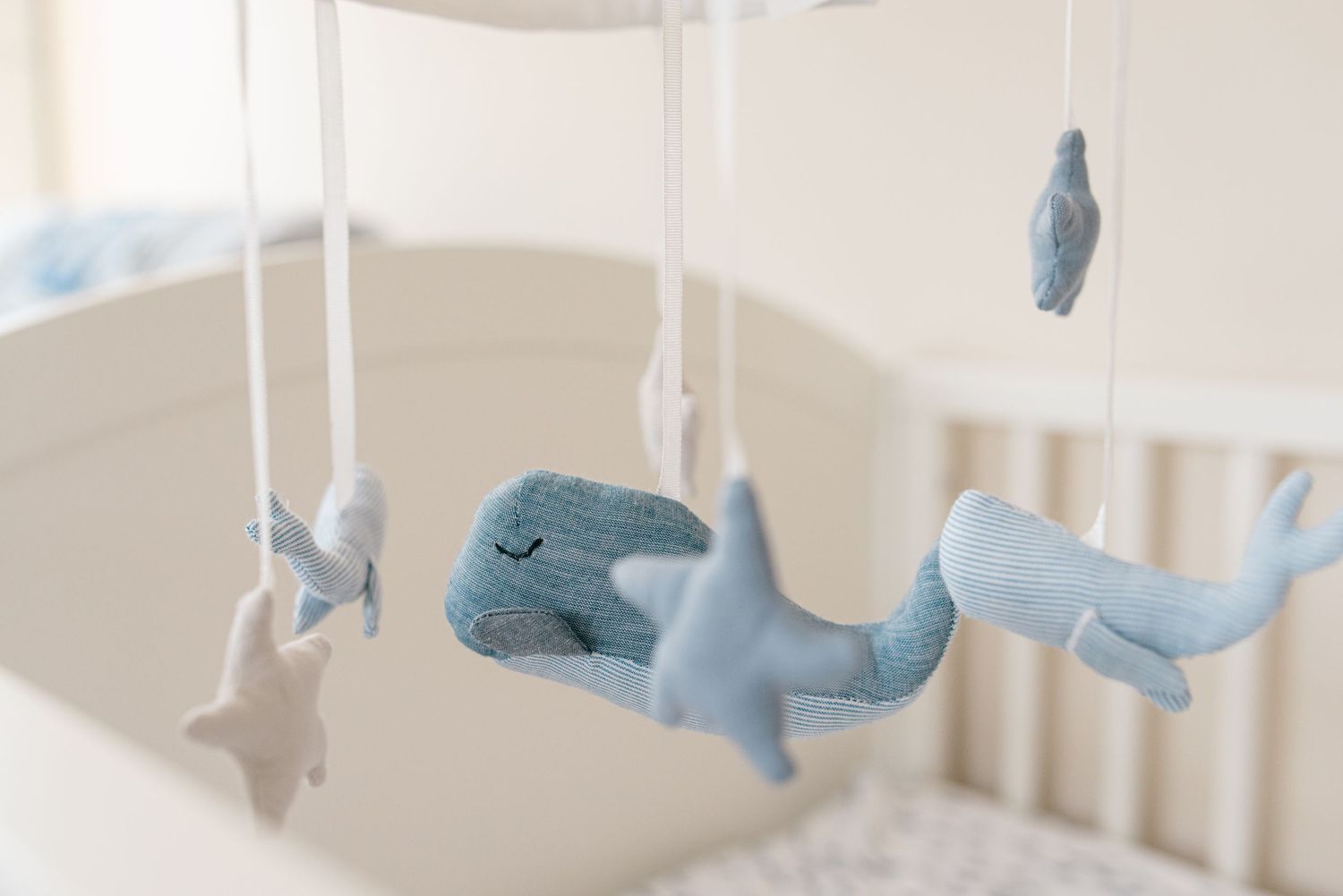 Hanging ocean theme whale and fish nursery mobile in tan crib.
