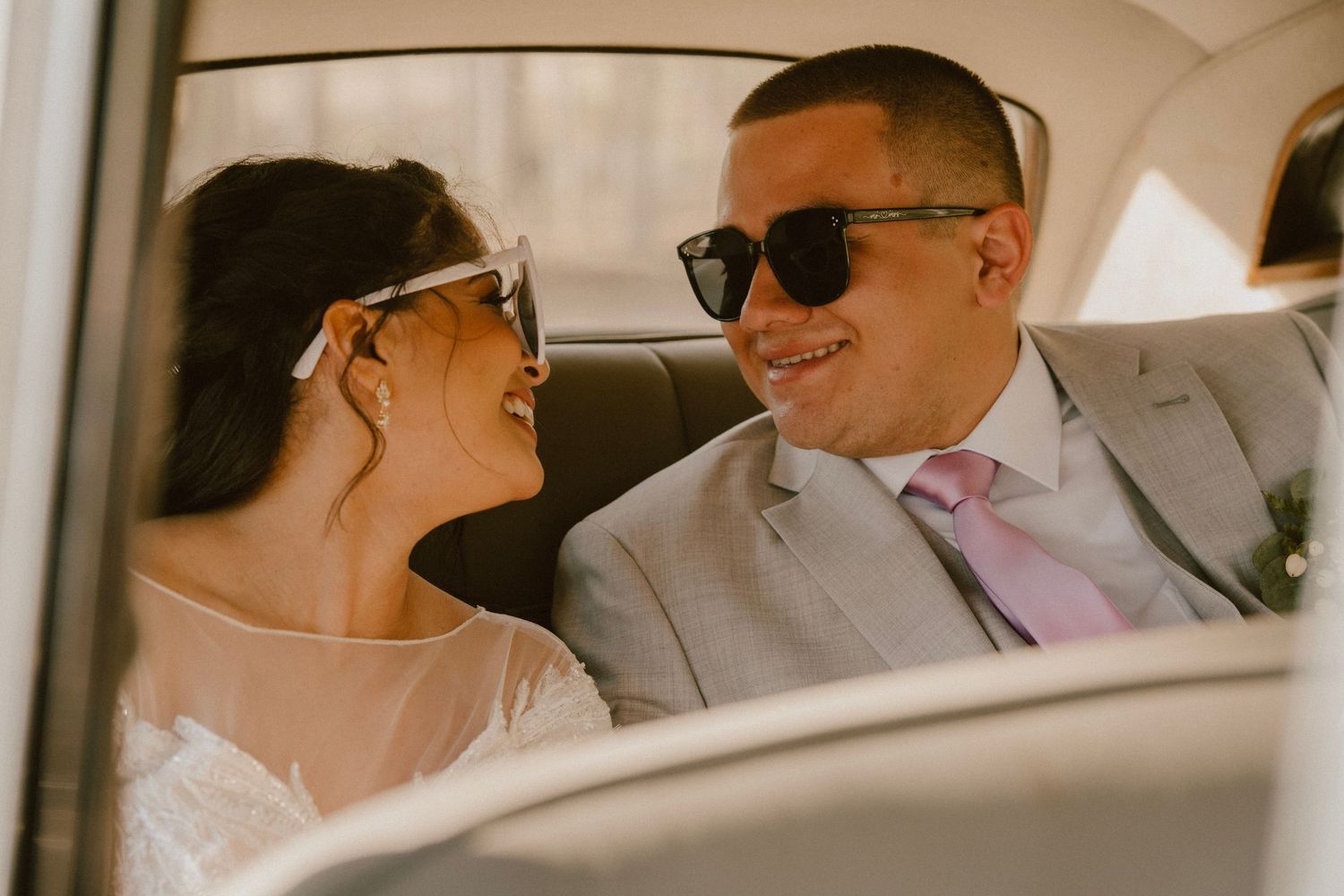 Couple shares intimate moment in backseat of car wearing formal wedding attire.