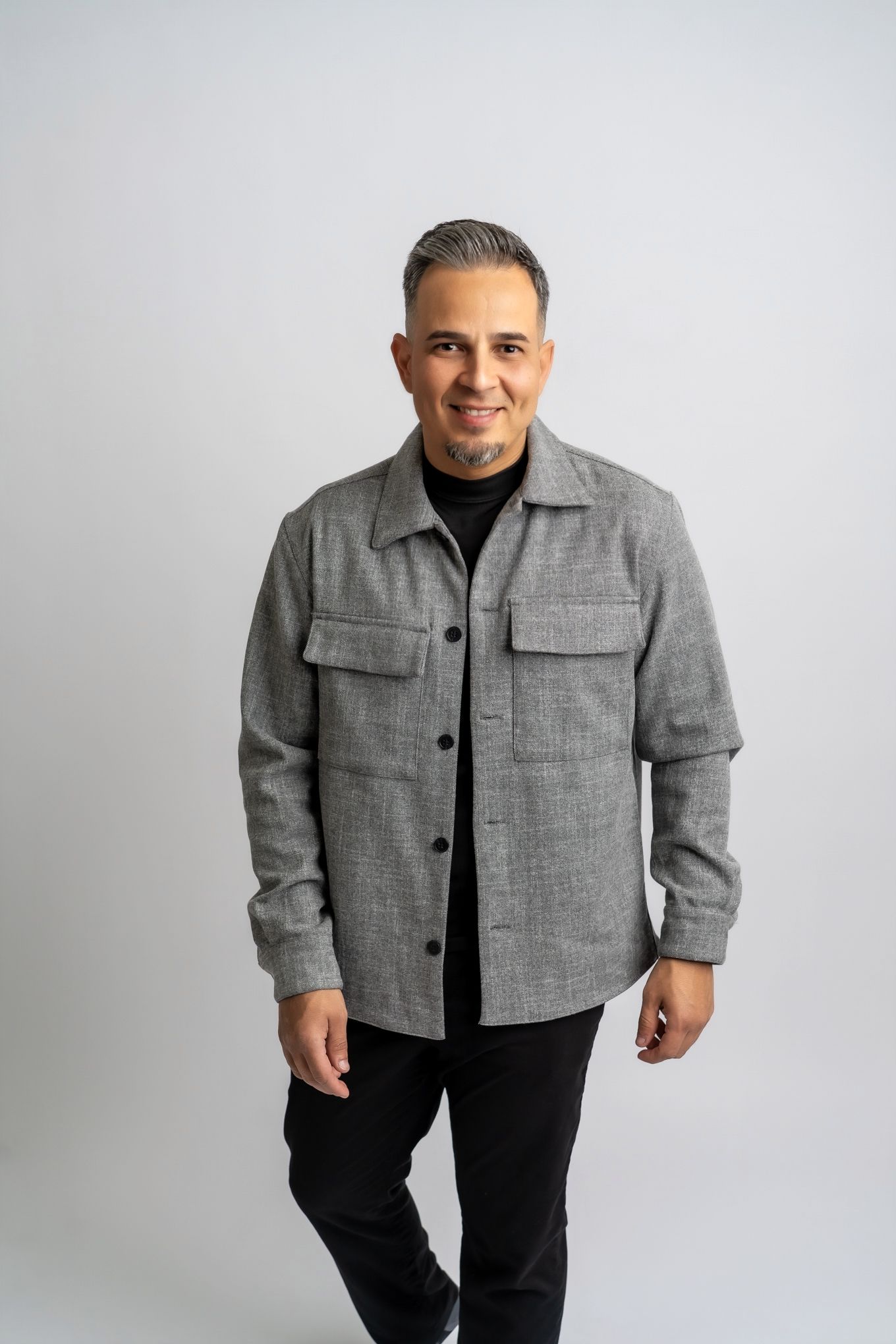 Casual portrait of person wearing gray button-up jacket against white background.