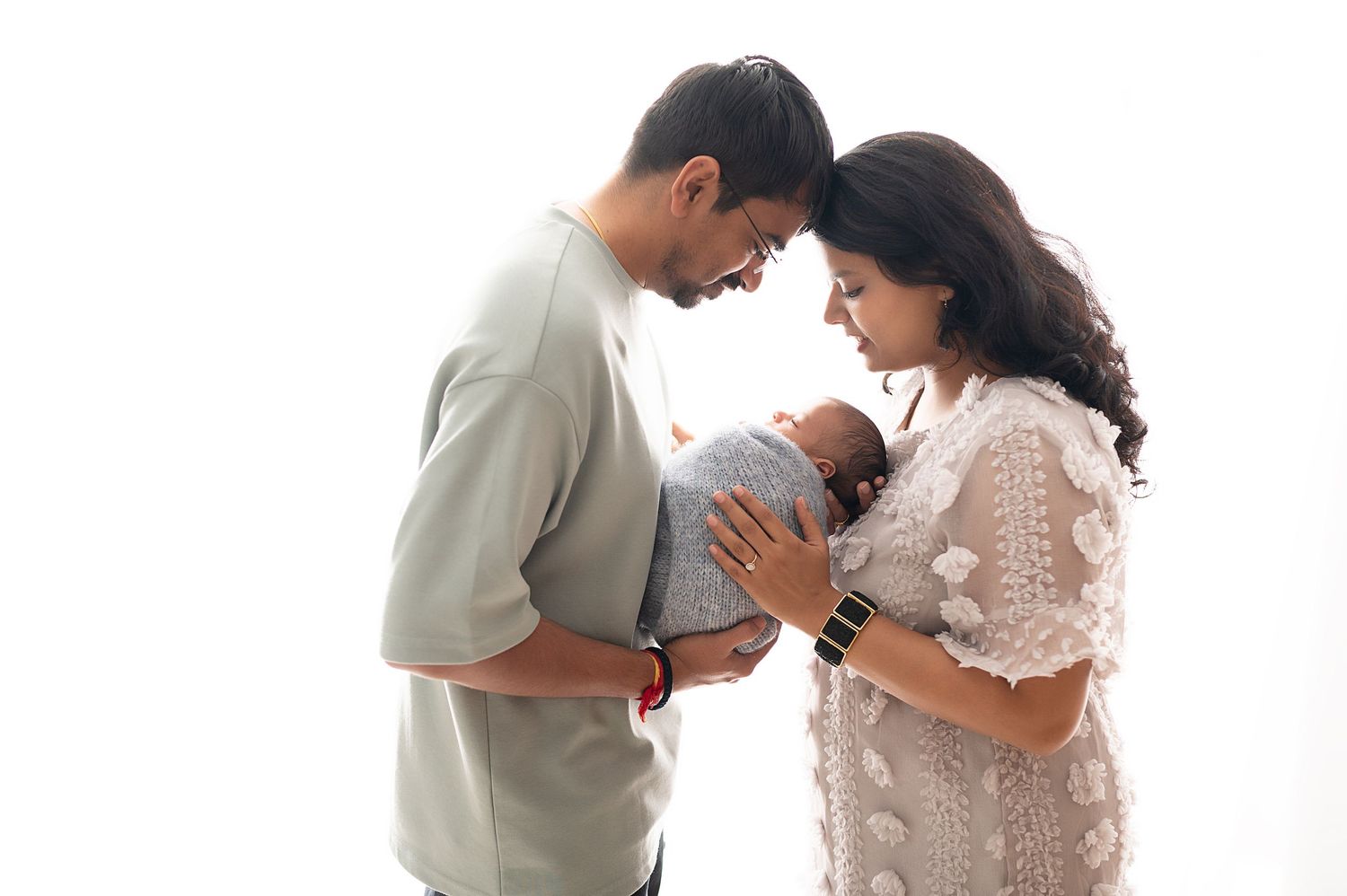 Parents sharing tender moment while holding their newborn baby.
