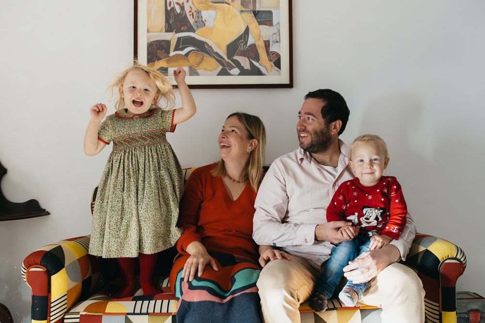 A family sits together on a colorful sofa in their living room, sharing a joyful moment while relaxing.