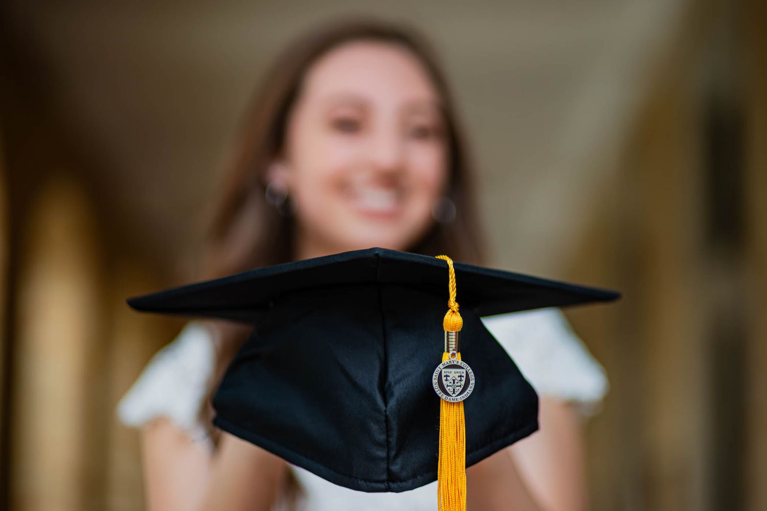 Graduation mortarboard with gold tassel photographed against soft focus background.