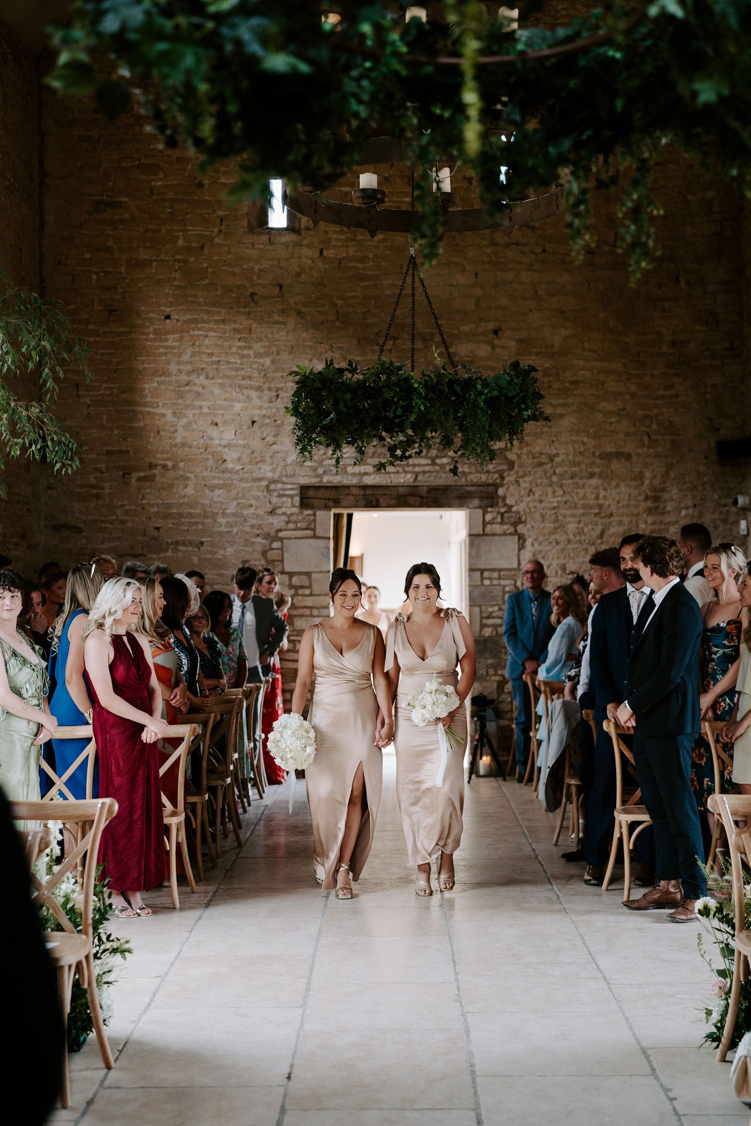 bridesmaids walking down aisle during wedding ceremony at yardspace old gore in cirencester