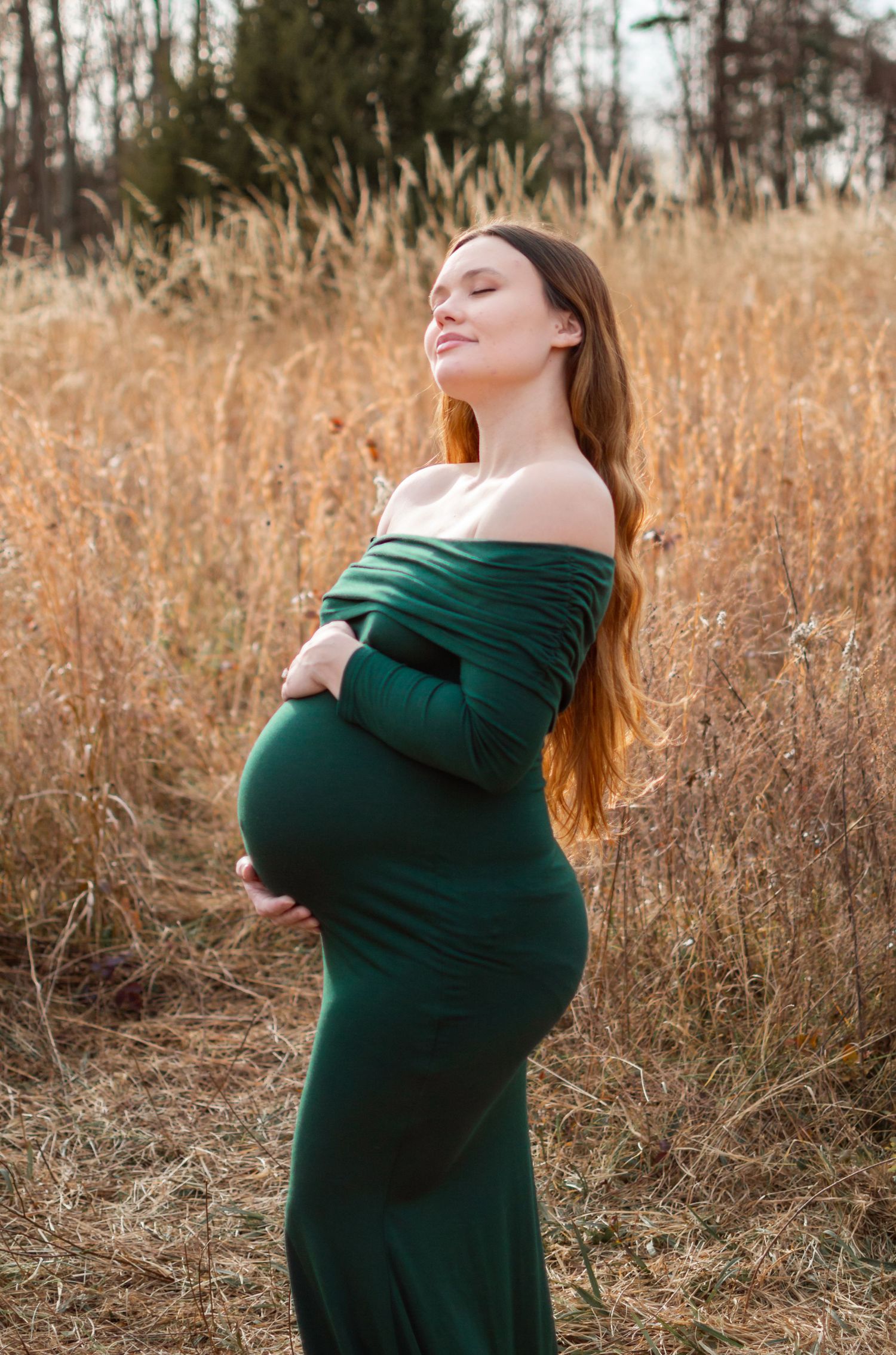 lady posed for maternity session in a grass field