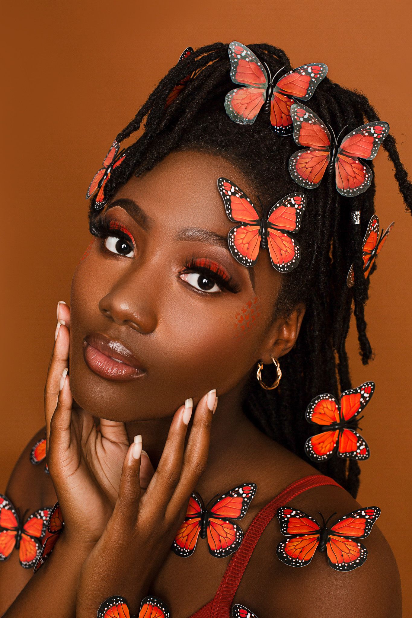 Artistic portrait with monarch butterflies against warm brown background showcasing natural beauty and delicate details.