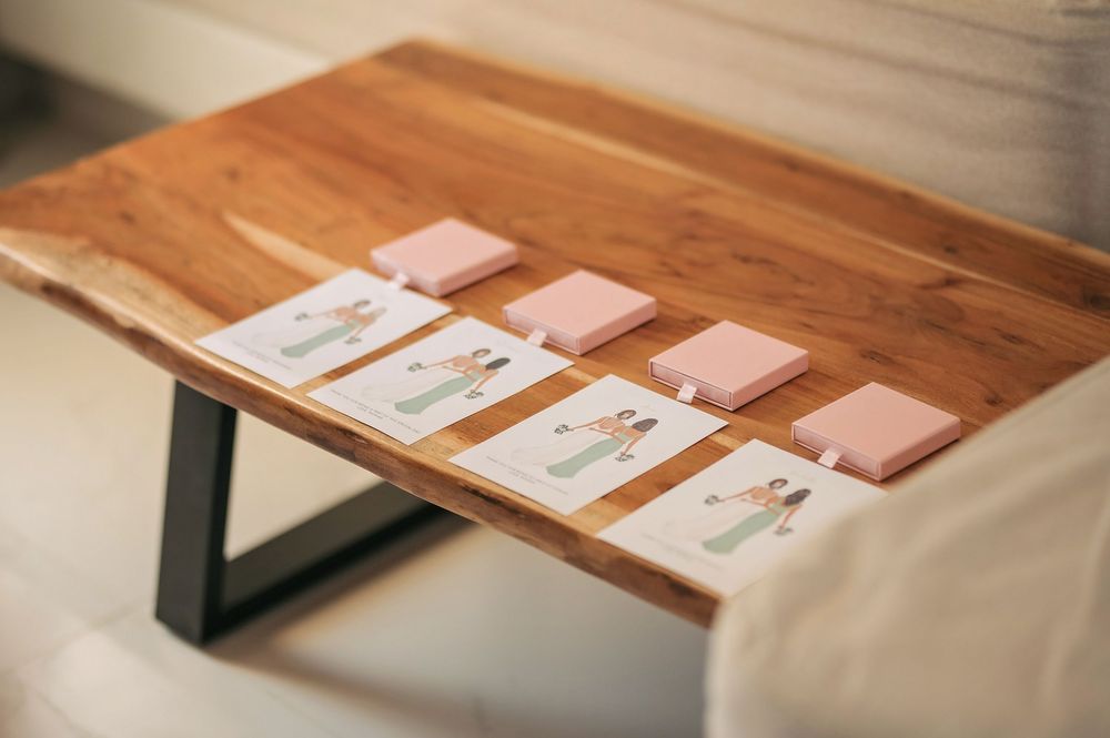 People looking at items displayed on wooden table with stone wall background.