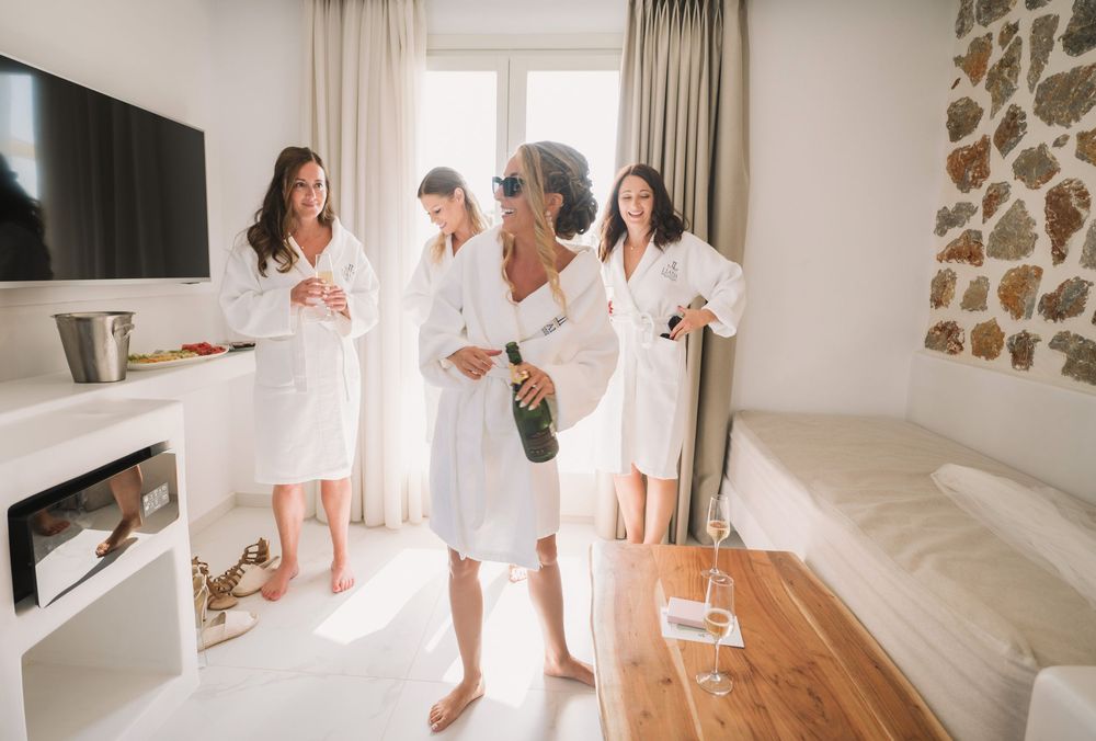Group in white robes gathering in bright modern room with stone accent wall.