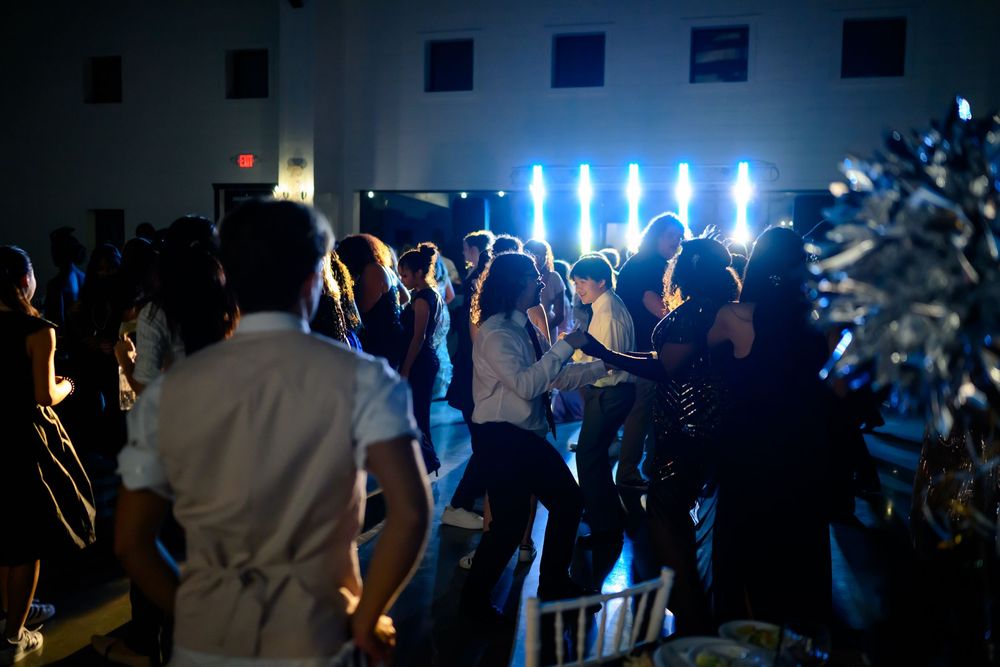 Party crowd dancing and having fun at a nightclub with blue stage lights illuminating the dark room.