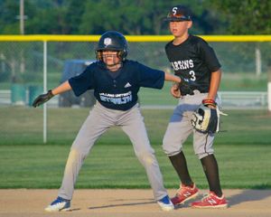 Two baseball players in game positions on the field with one taking a lead off base.