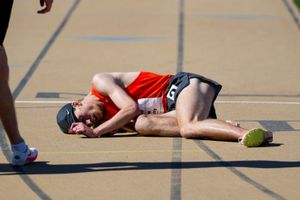 Exhausted athlete lies on track after intense competition.