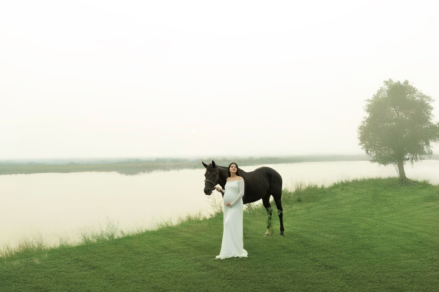 Maternity photoshoot Noida solo mom studio portrait

A black horse standing beside flowing white fabric against a misty lakeside landscape.