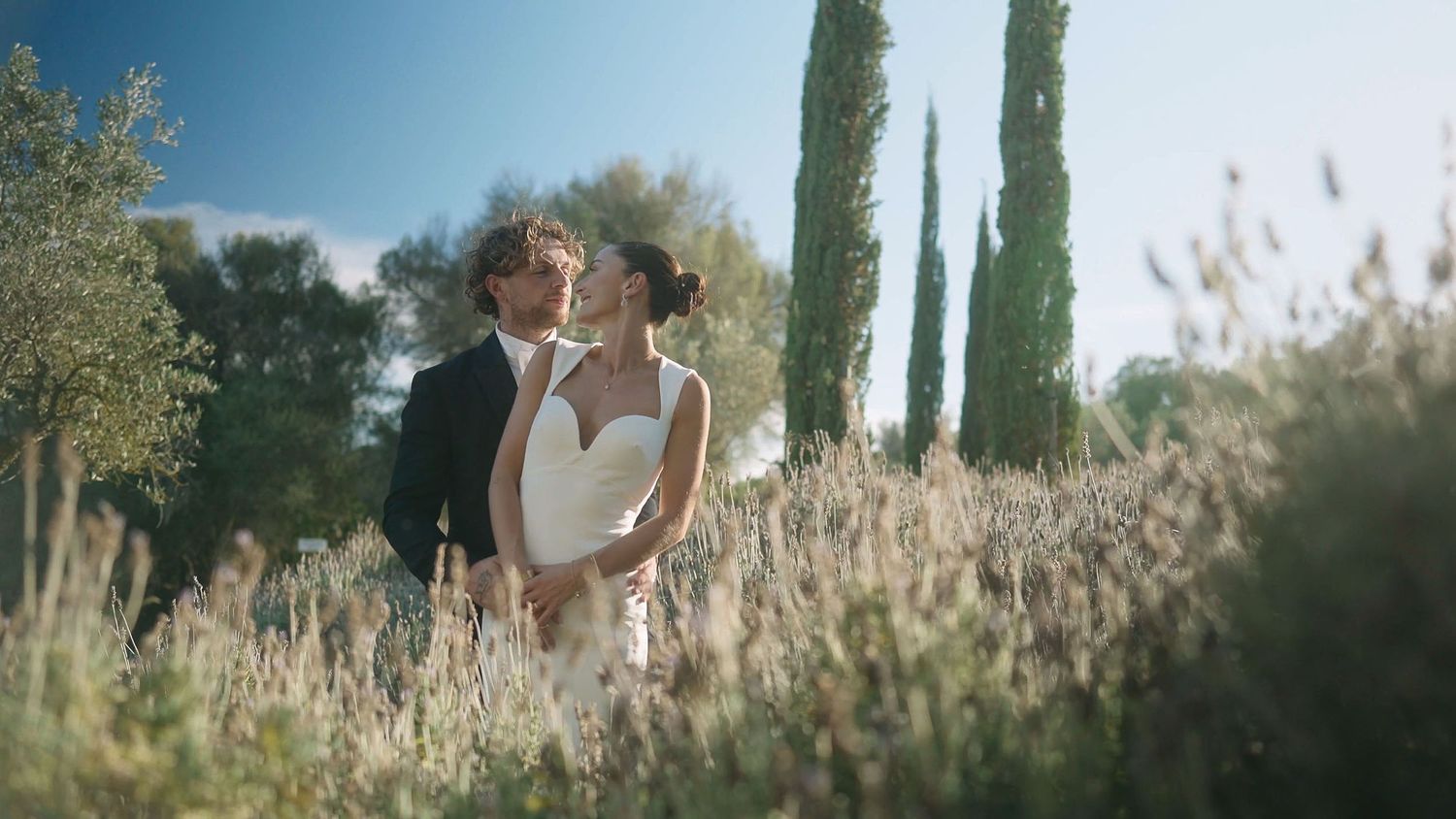 Newlywed couple in a lavender field, surrounded by nature and soft light.