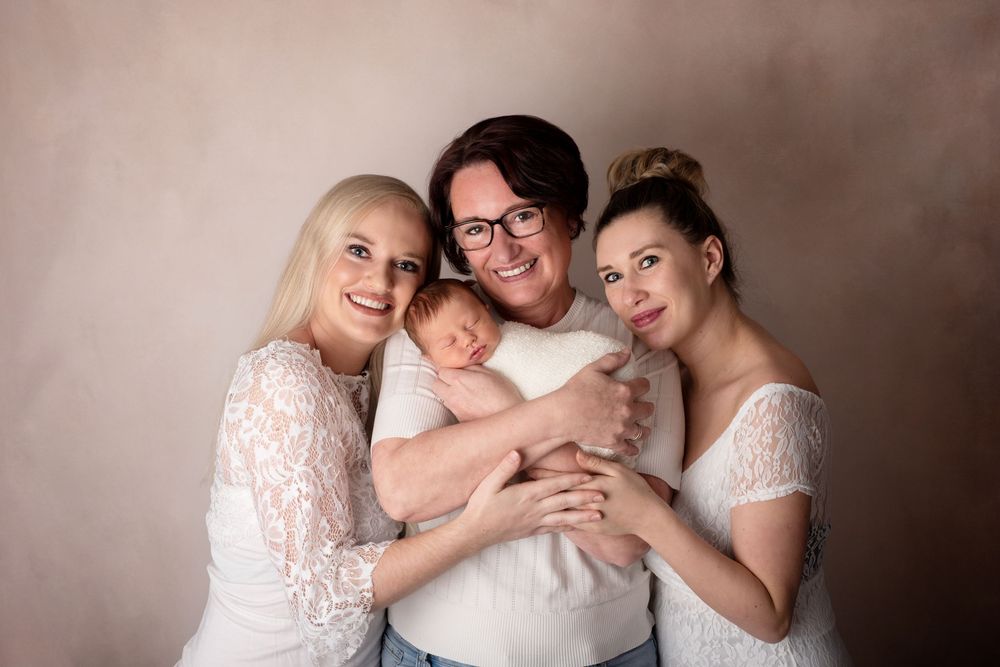 Studio portrait of family  in white lace outfits against neutral background.