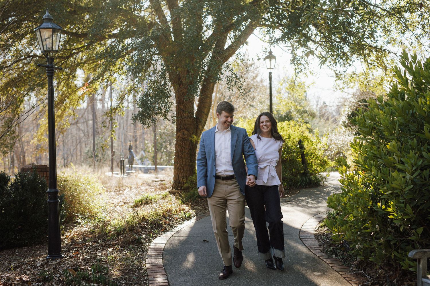 People walking along a tree-lined path on a sunny autumn day.