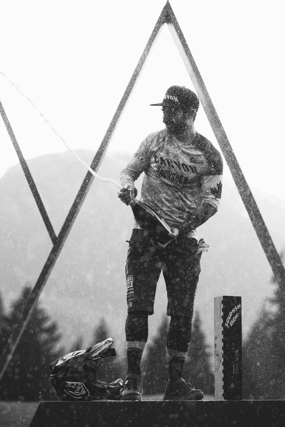 Silhouetted figure stands on geometric platform against misty mountain landscape in black and white photography.