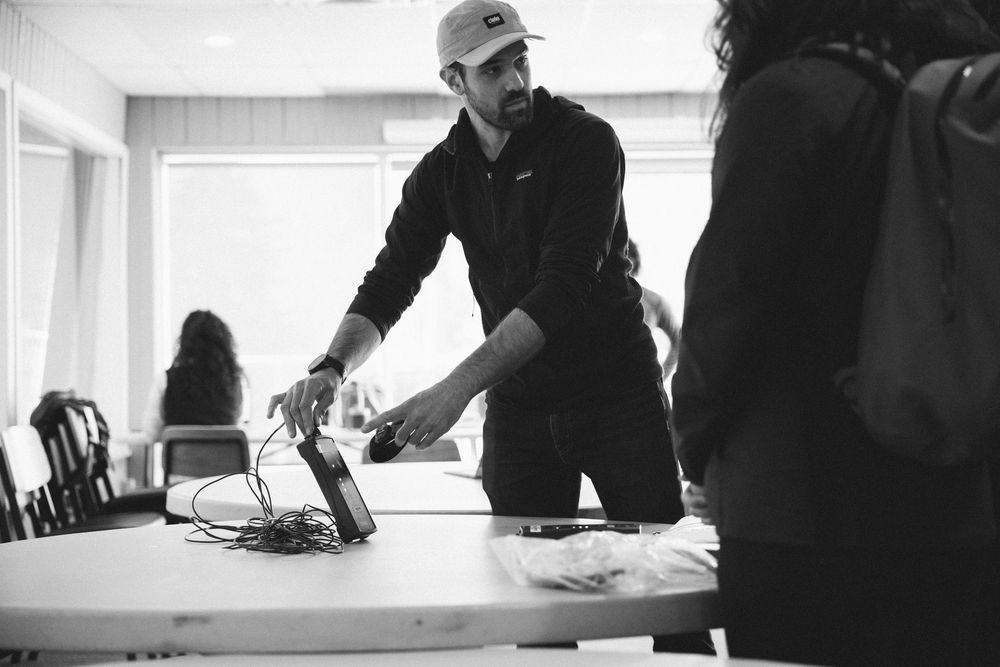 Three people work around a table in an office setting reviewing documents in black and white photography.
