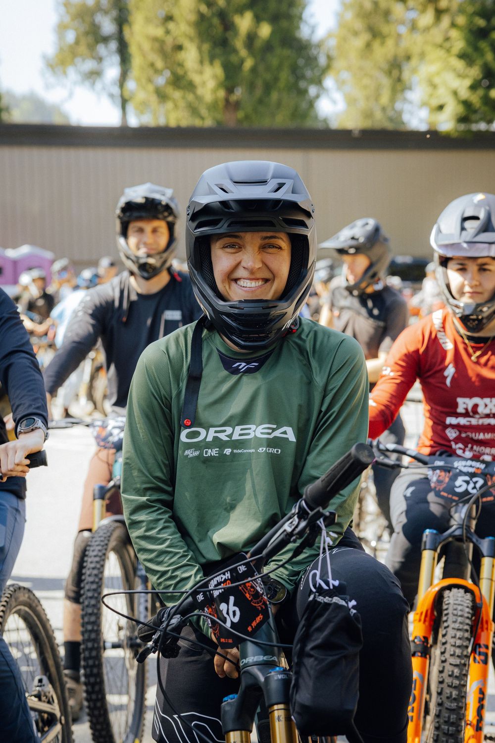 Group of mountain bikers gathered at an event wearing protective gear and helmets.