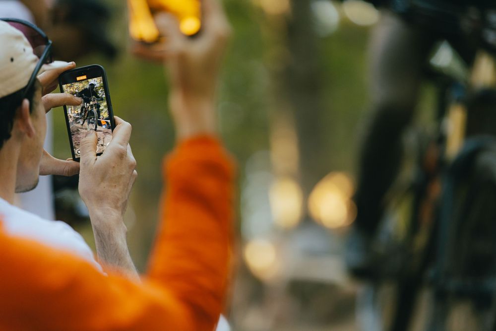 Person holding smartphone to capture action sports photography in outdoor setting.