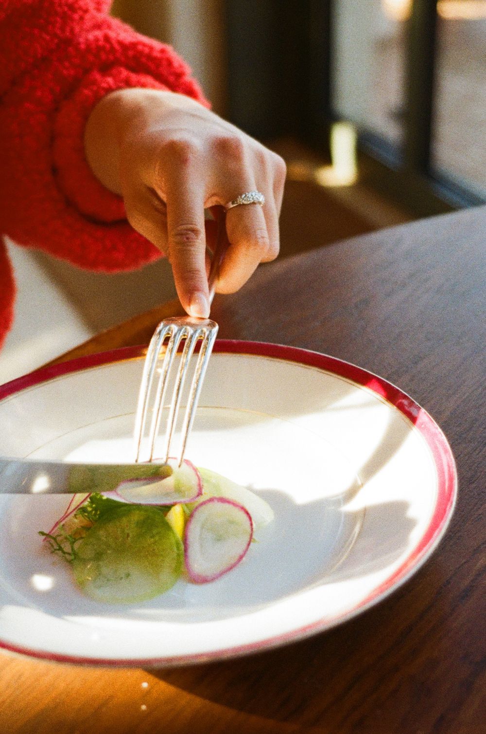 Three close-up photos of hands holding a silver fork over a white plate with small garnish and colorful accent.