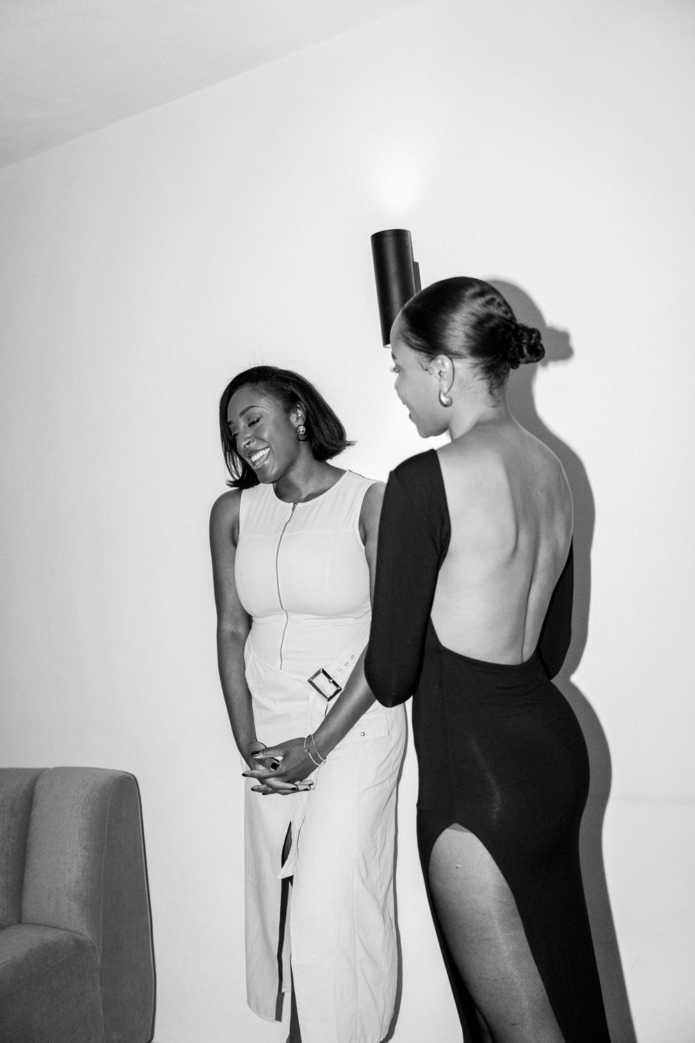 Two models pose in black and white leotards against a white studio backdrop.