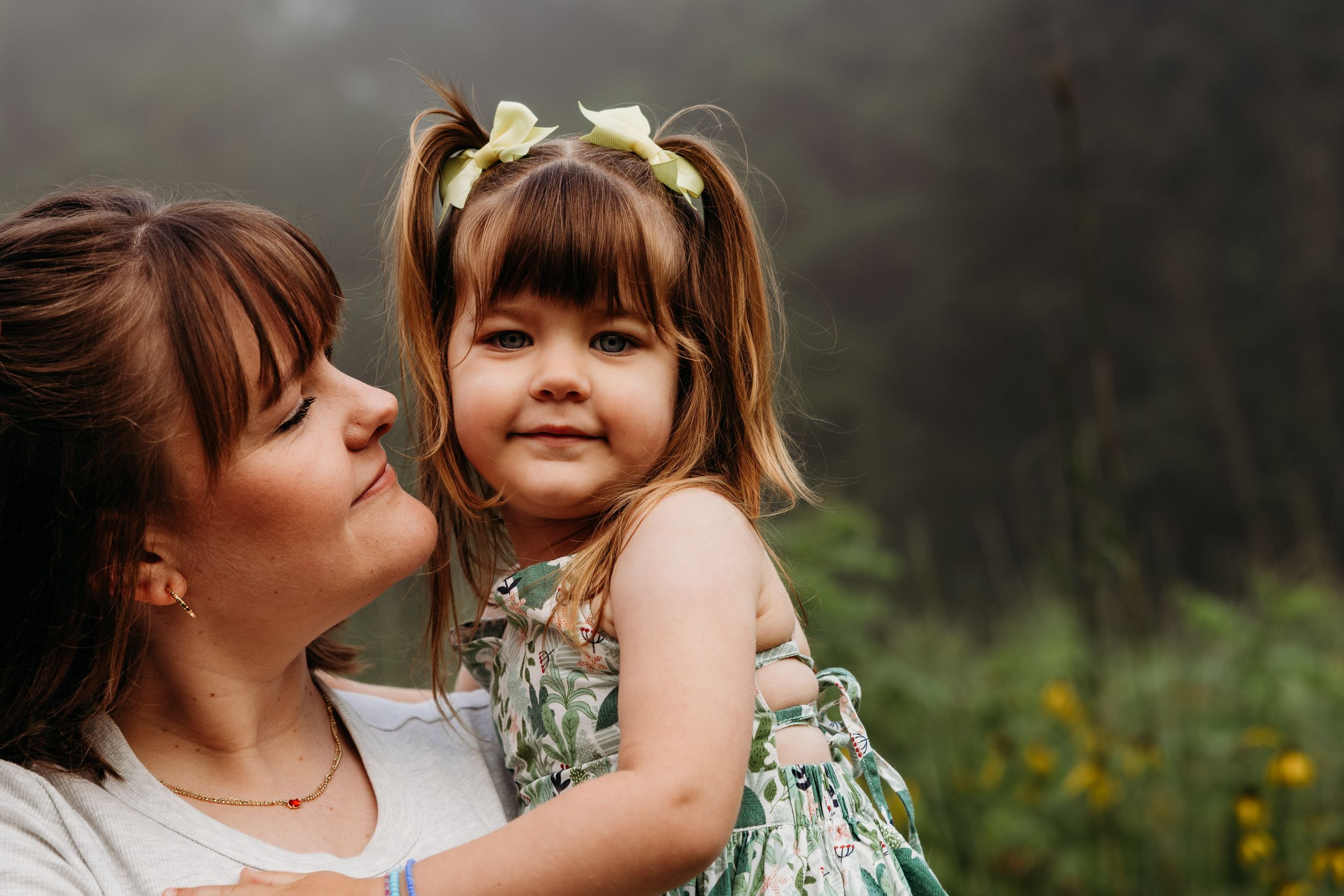 A heartfelt moment between parent and child outdoors with soft lighting and floral dress details.