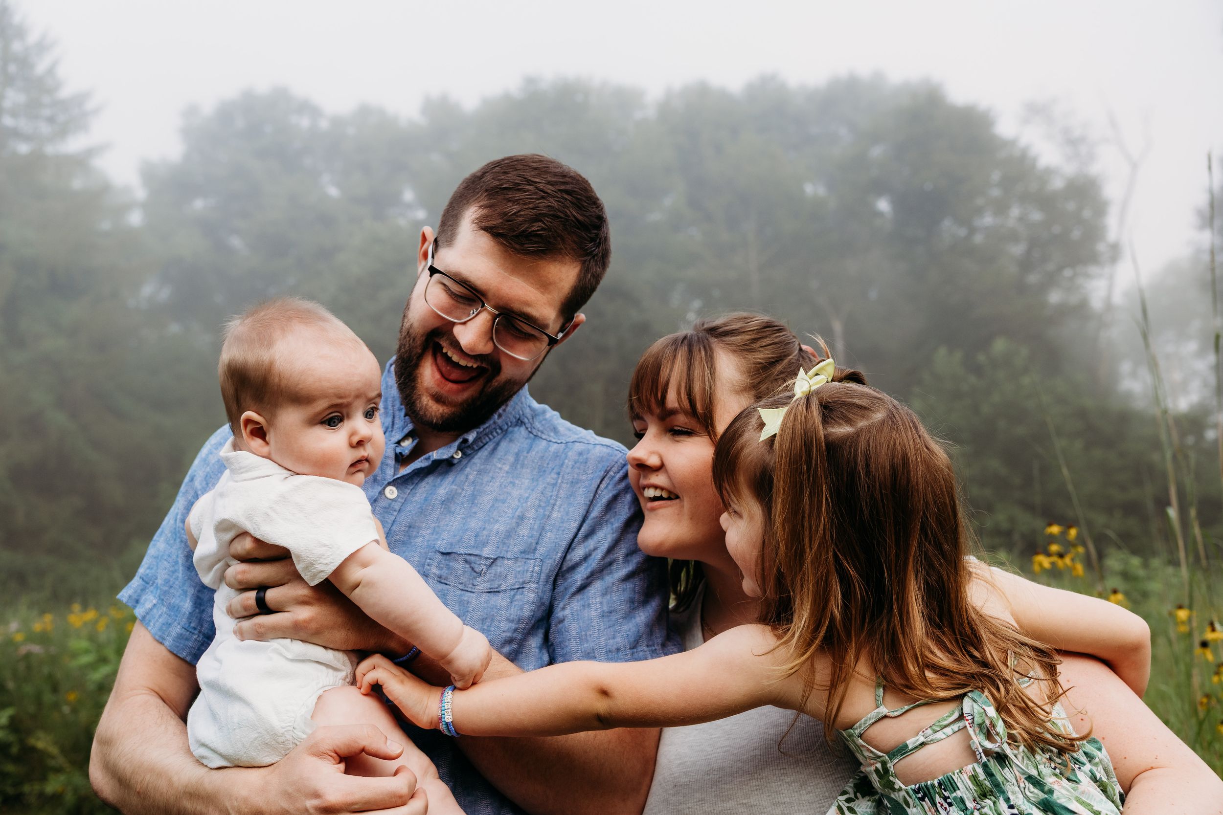 A family shares joyful moments together while sitting outdoors in a foggy natural setting.