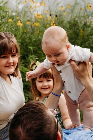 Playful sequence of parent lifting baby into the air while both smile and laugh in an outdoor setting.