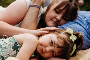 Two people laying down together outdoors in a tender moment while wearing spring-colored clothing.
