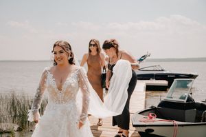An elegant outdoor beach wedding with small aircraft, boats, and classic cars in the background.