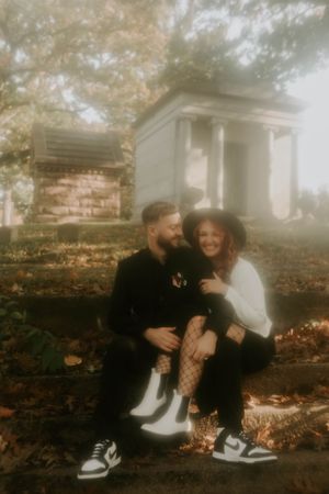 A couple sits together on brick steps during a foggy autumn day.