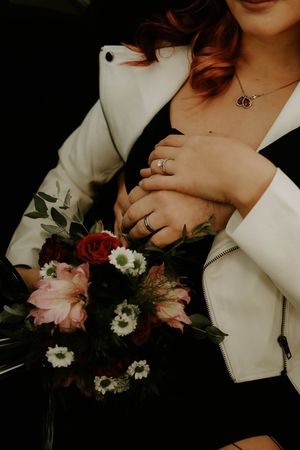 Close-up details of white flowers and fashion accessories against dark background.