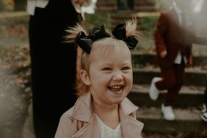 Child smiling brightly during an outdoor autumn photoshoot.