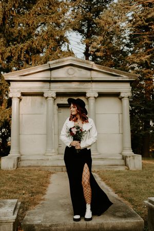Couple embraces near stone mausoleums during a moody autumn photoshoot.