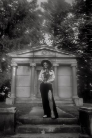 Black and white photo of a couple posing near cemetery mausoleums.