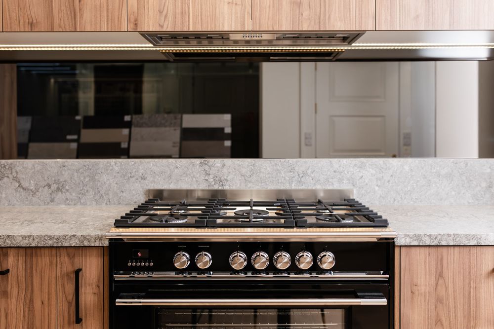 Modern kitchen featuring sleek appliances and gas cooktop with stainless steel controls mounted on marble countertop.