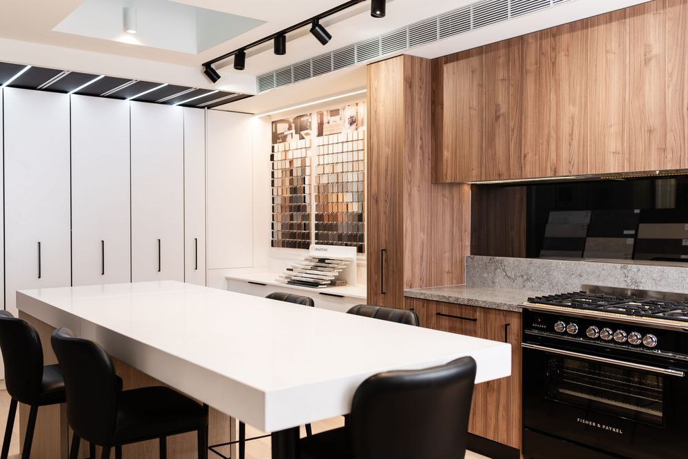 Open concept kitchen with track lighting, wooden cabinets, and white countertops in modern design.