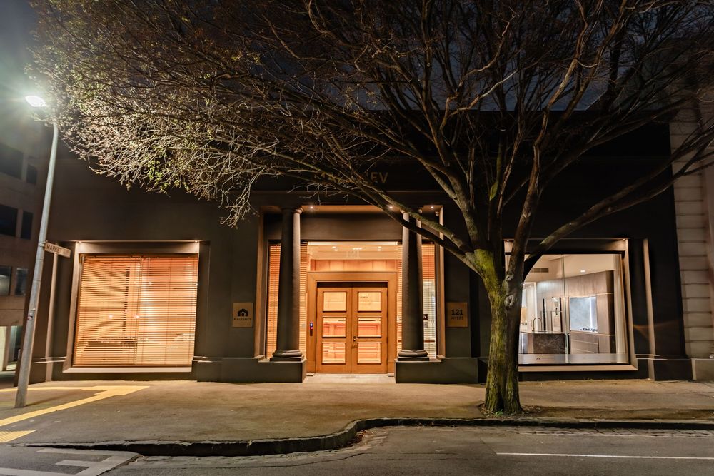 Residential exterior at night with illuminated doorways and trees creating atmospheric ambiance.