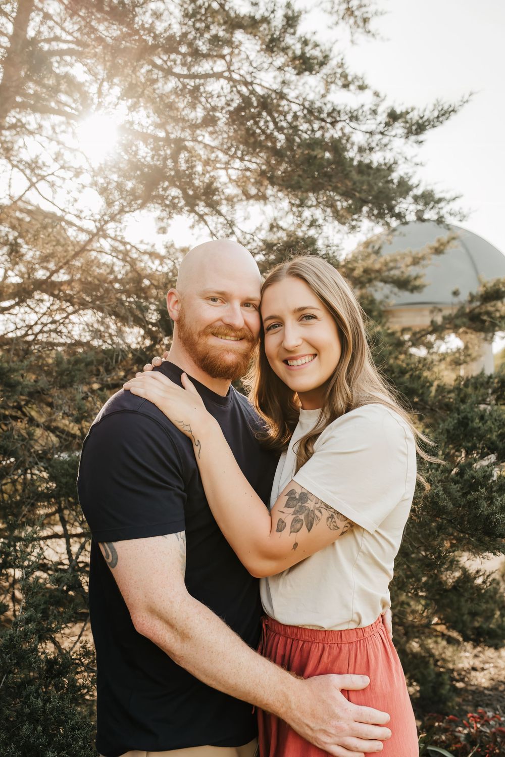 boyfriend and girlfriend snuggle up as sun sets romantically in the back