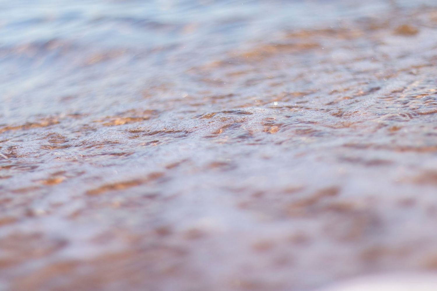 Abstract close-up of rippling water with warm golden tones and soft texture.