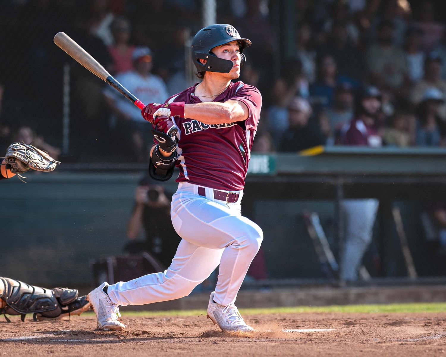 Baseball player in pink uniform swings bat during game as ball approaches from pitchers mound.