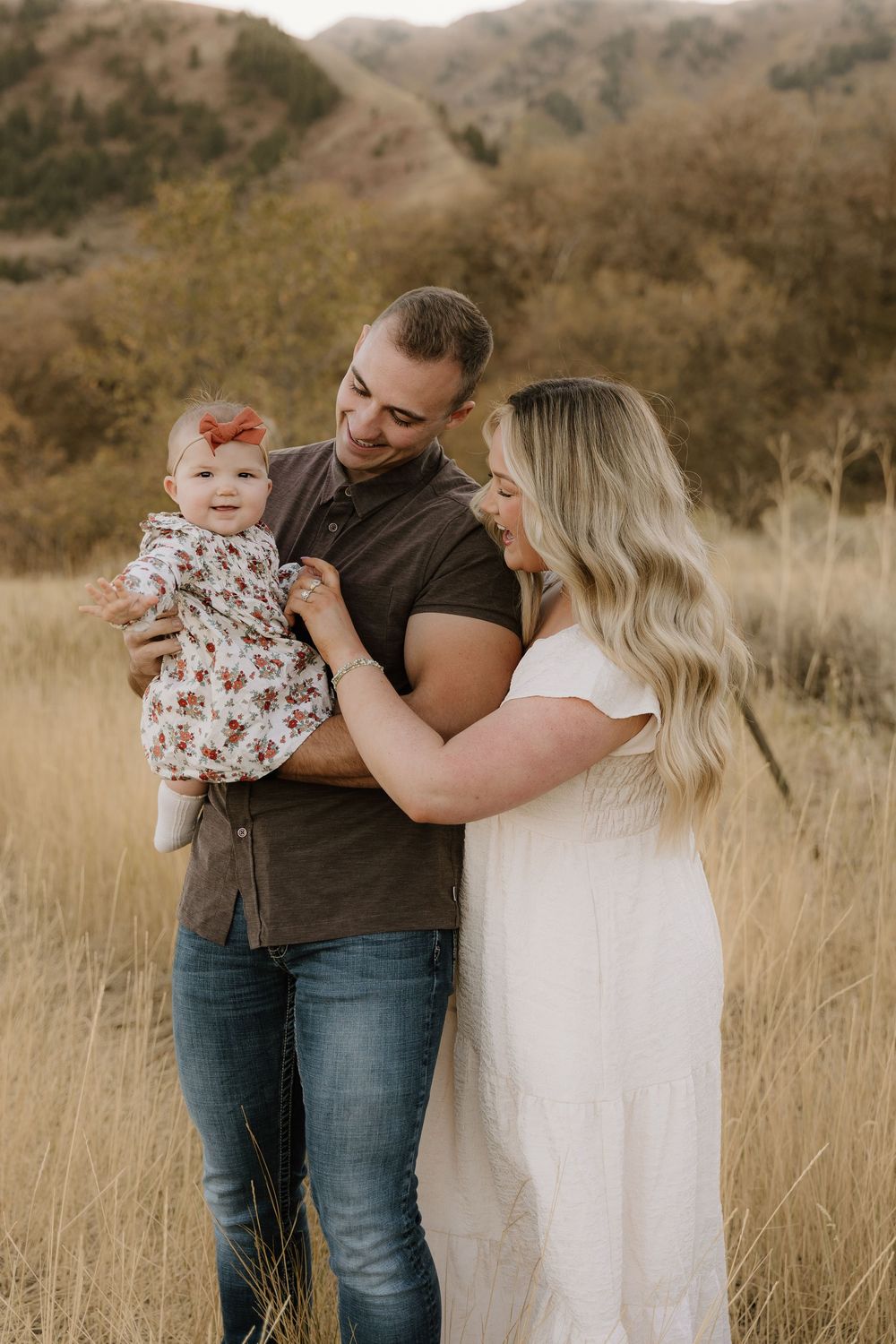 Family shares intimate moments together in a rustic mountain field at golden hour.