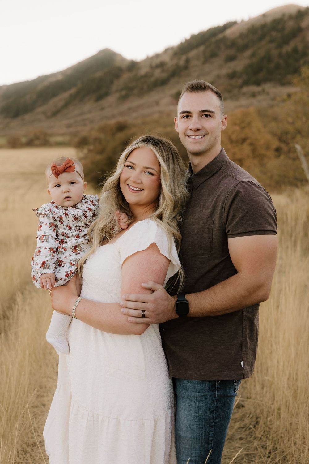 Sweet family portrait session in tall grass against mountainous backdrop.