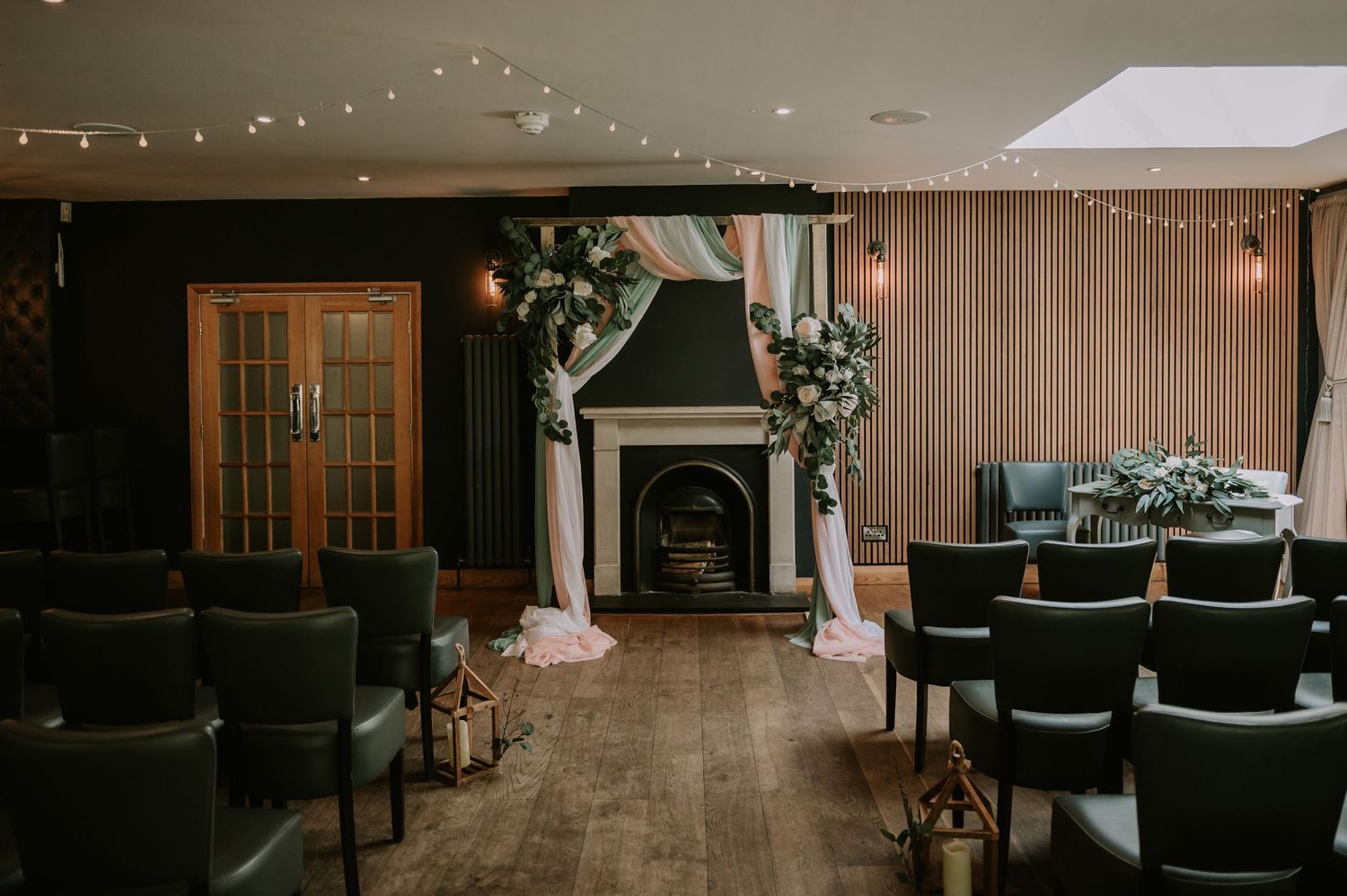 A wedding venue being set up, featuring a large arch draped in white fabric with floral arrangements at each corner, all ready for a wedding